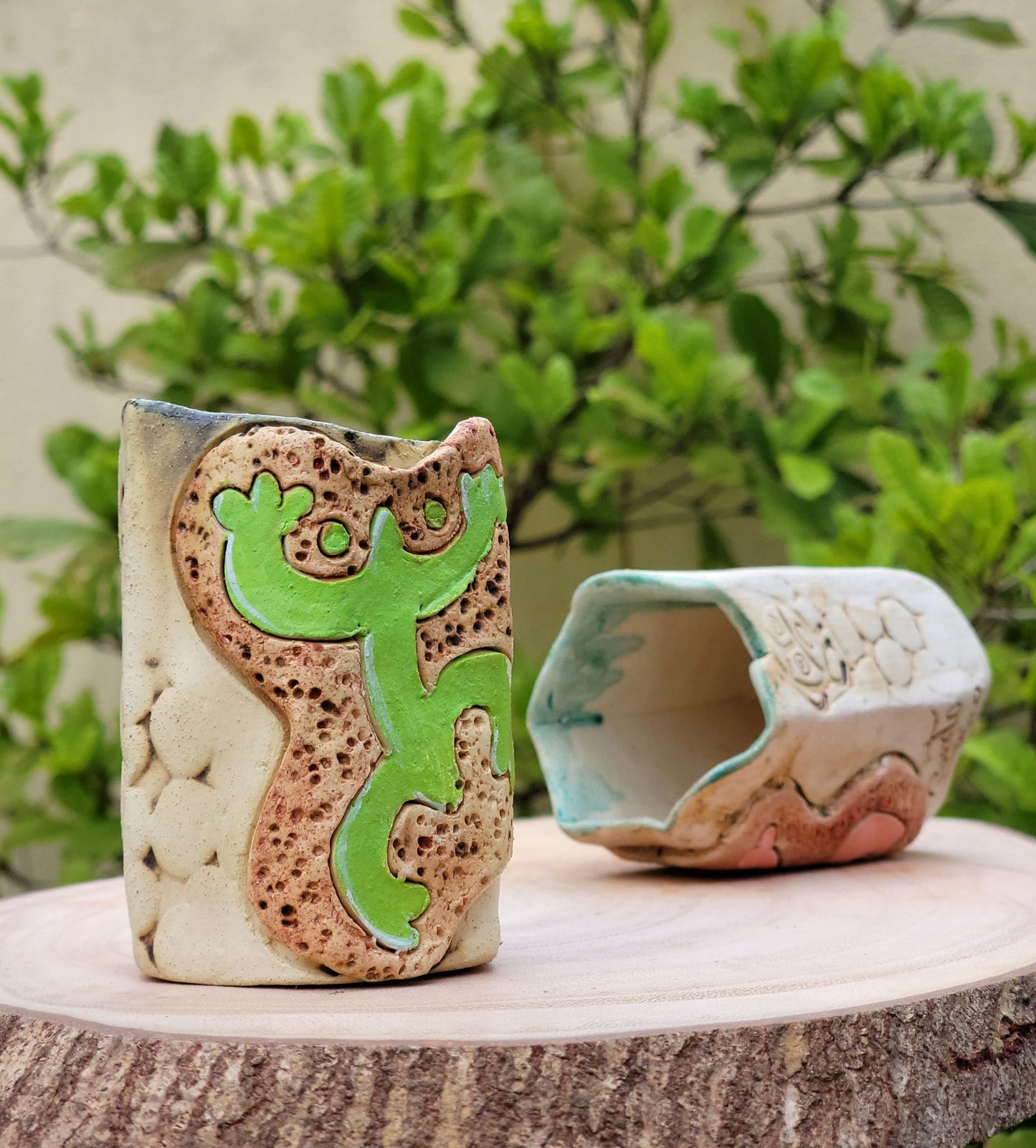 Ceramic gecko and cave sculpture on a wooden surface with a natural background