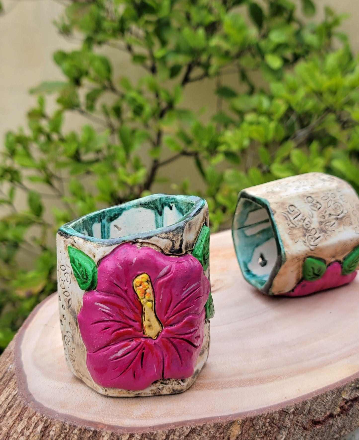 Decorative ceramic hexagonal piece with floral designs on a blurred natural background