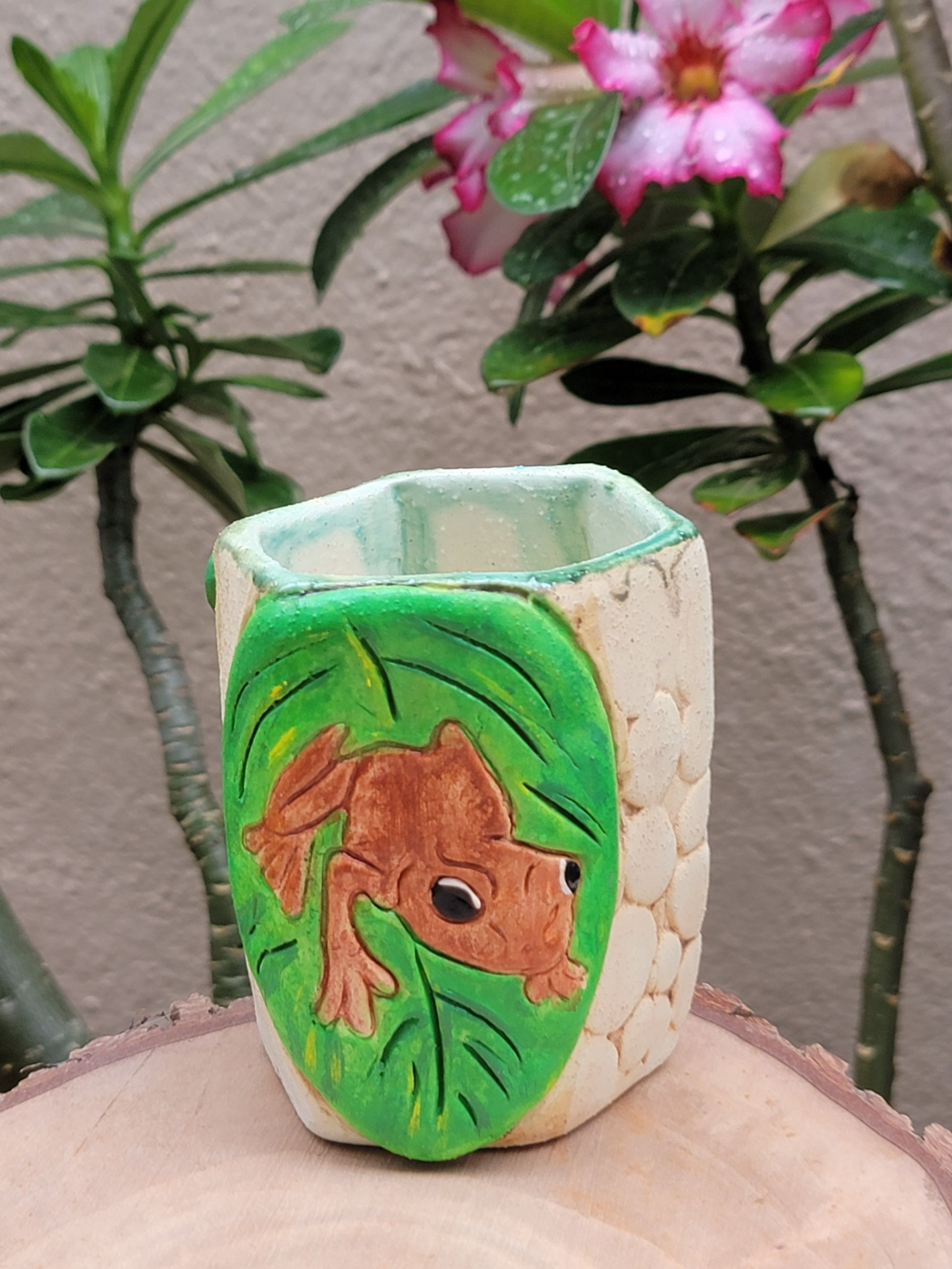Decorative handmade ceramic Coqui frog hexagonal holder with a wooden surface