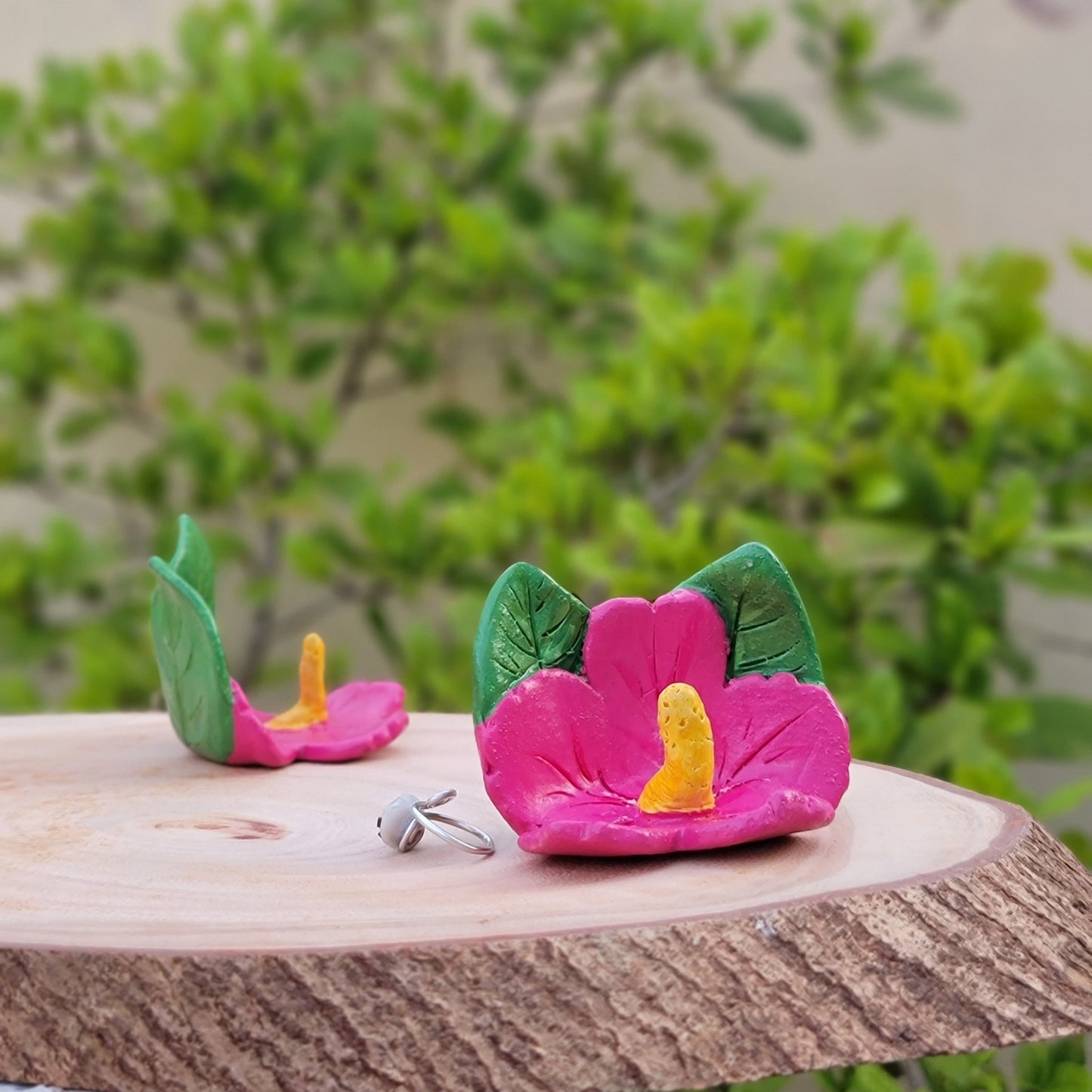 Pink Flower-shaped design on a wooden post against a green plant background