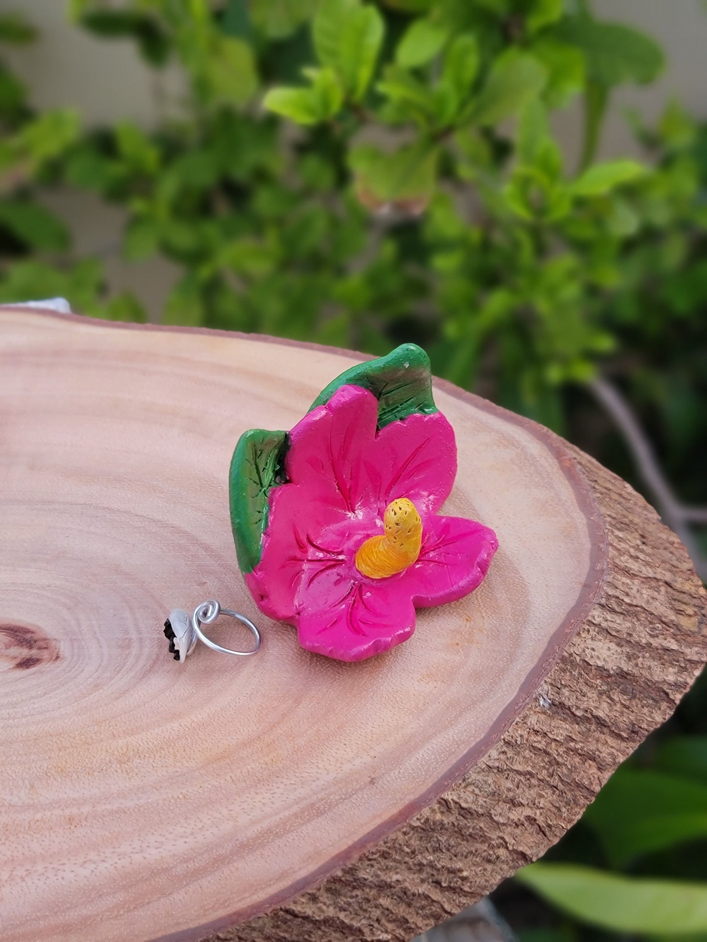 Pink flower on a wooden block with blurred greenery in the background