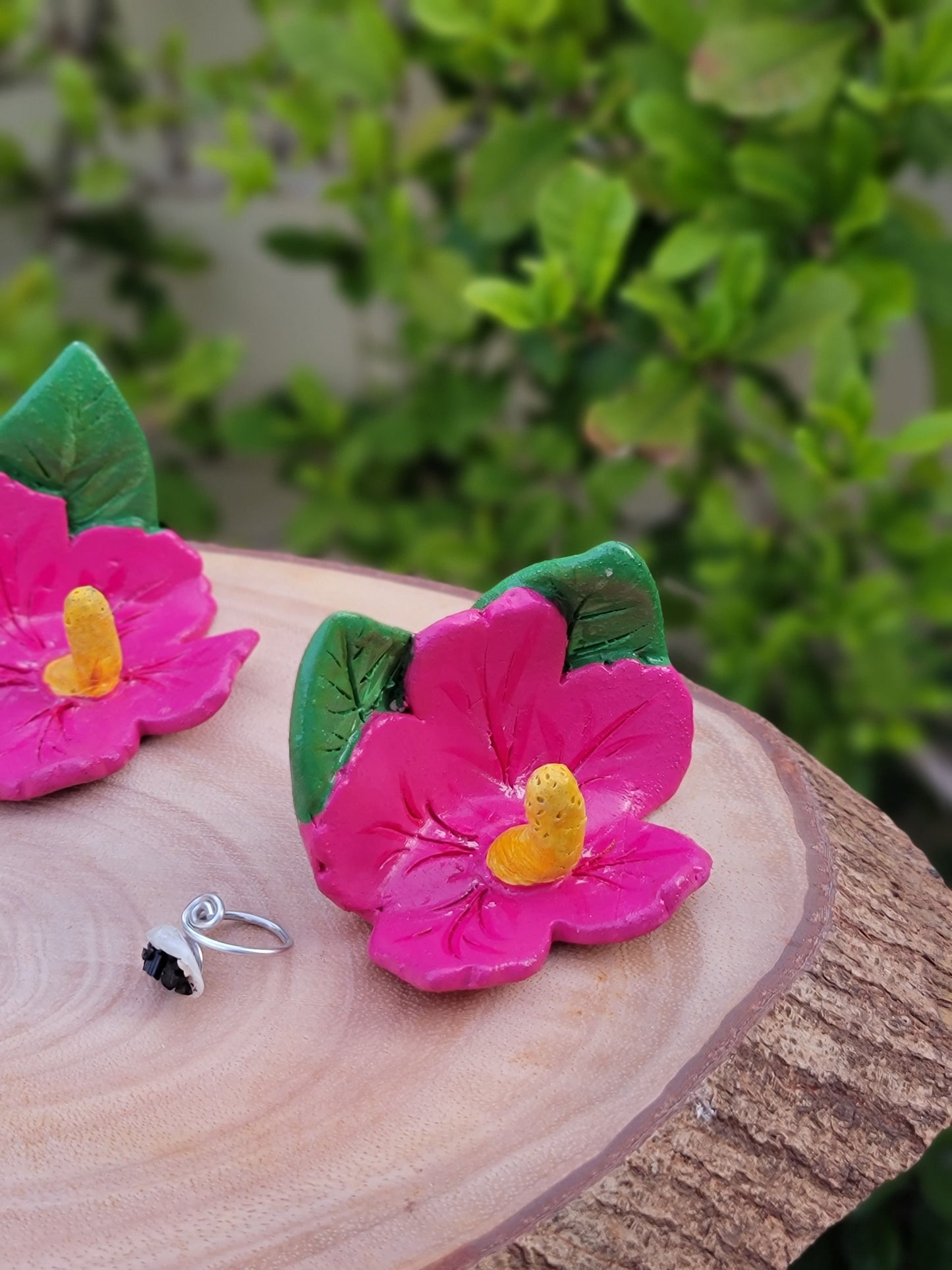 Pink flowers on a wooden surface with green leaves in the background