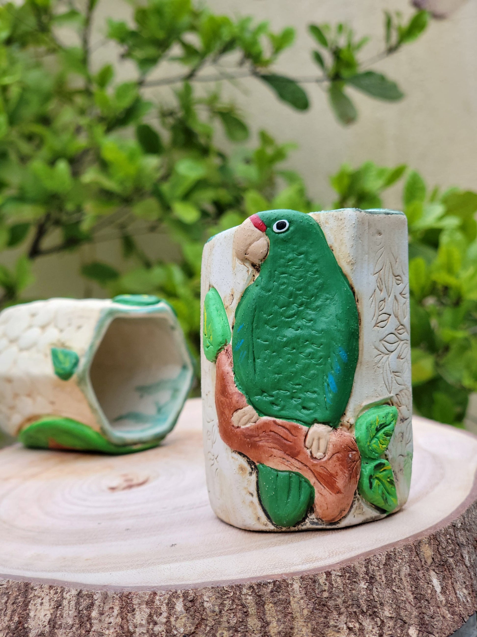 Decorative ceramic green parrot design with a plant in the background