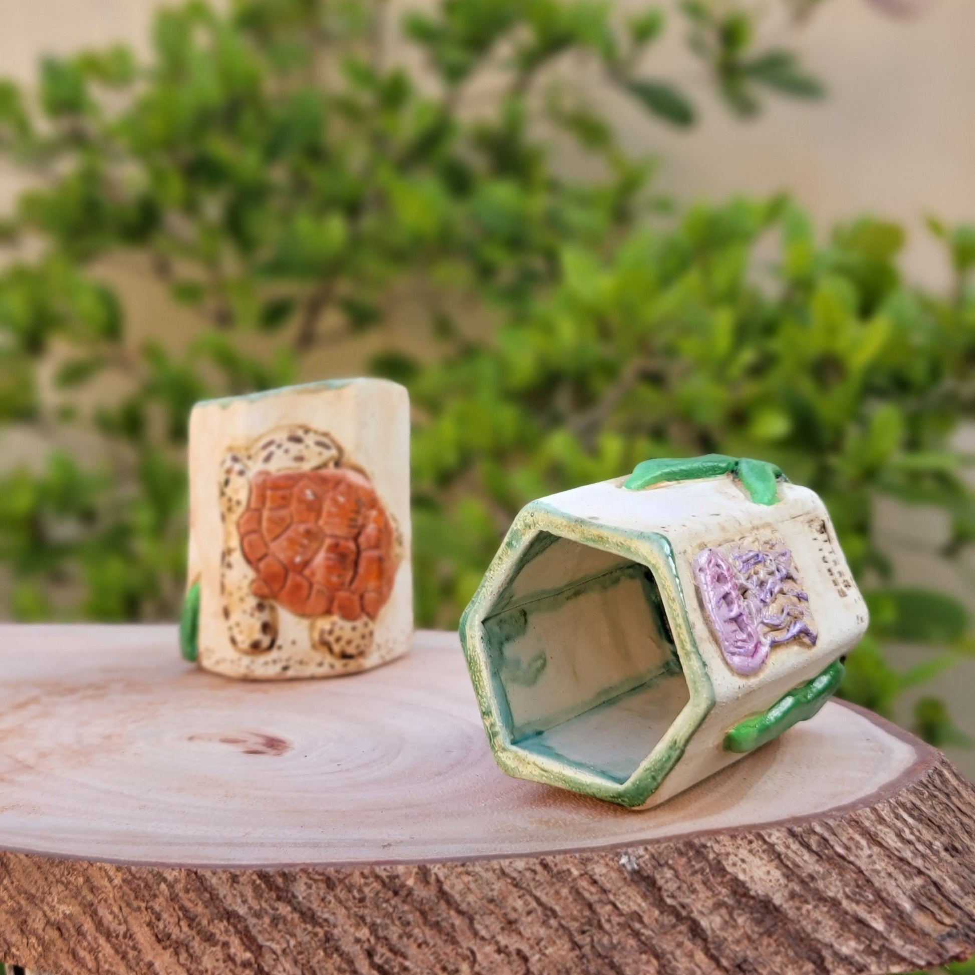 Two small hexagonal ceramic objects with decorative patterns on a wooden surface.