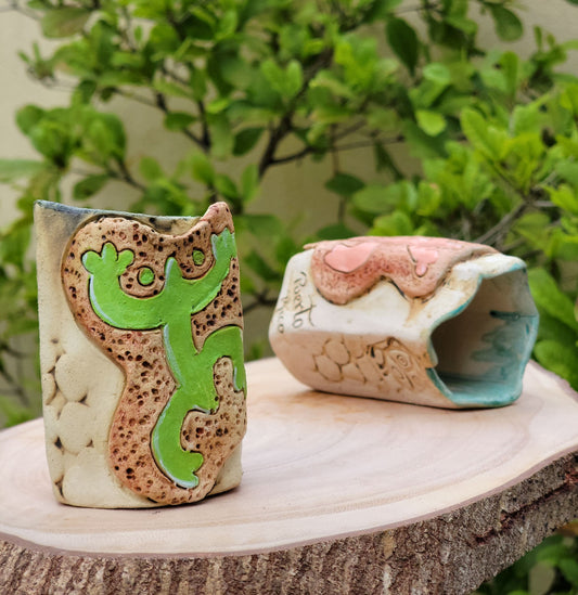 Two ceramic pieces on a wooden surface with a natural background