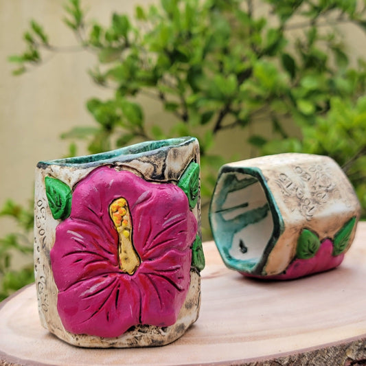 Decorative ceramic hexagonal piece with floral designs on a blurred natural background
